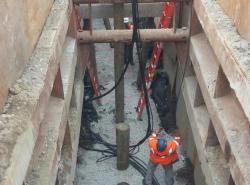 A work crew installing piles to support new sewer and drain pipes