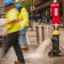 A fire hydrant open with water pouring out; being flushed